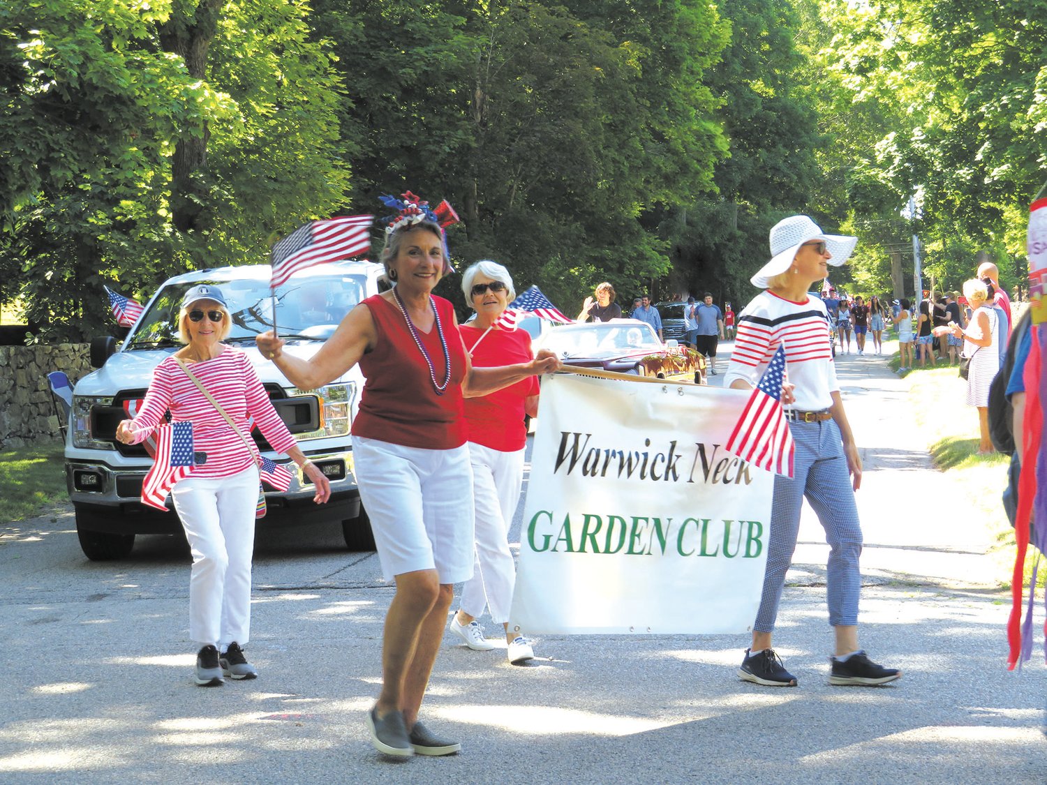 APPRECIATED BY MANY: Bernadine DiOrio and Ann Dougherty carry the Warwick Neck Garden Club banner. Among its projects the club maintains the garden entry to the Neck from West Shore Road.